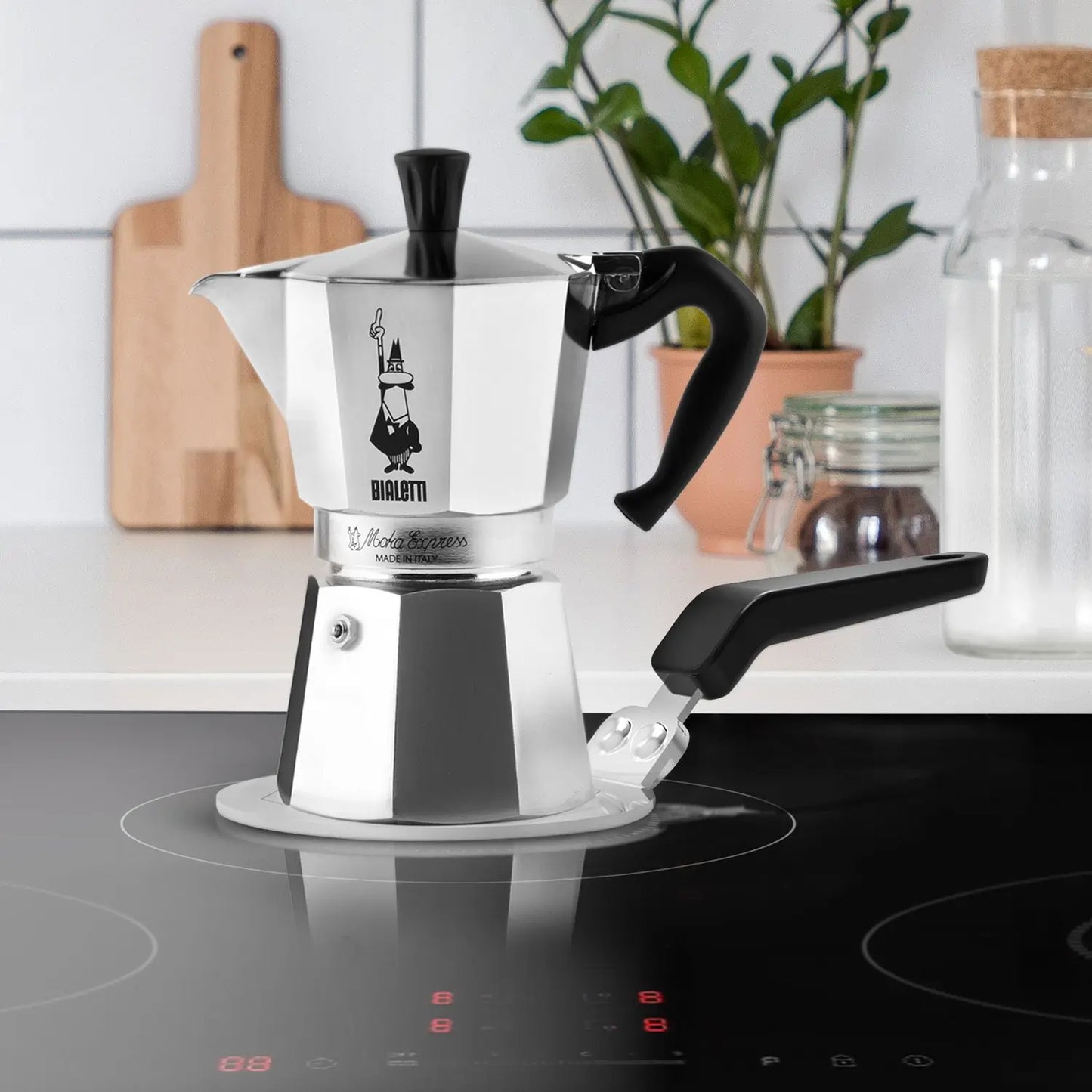 Adapter indukcyjny Bialetti 13 cm używany z kawiarką Moka Express na płycie indukcyjnej, stalowa płyta grzewcza z uchwytem, zdjęcie lifestyle