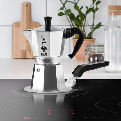 Adapter indukcyjny Bialetti 13 cm używany z kawiarką Moka Express na płycie indukcyjnej, stalowa płyta grzewcza z uchwytem, zdjęcie lifestyle
