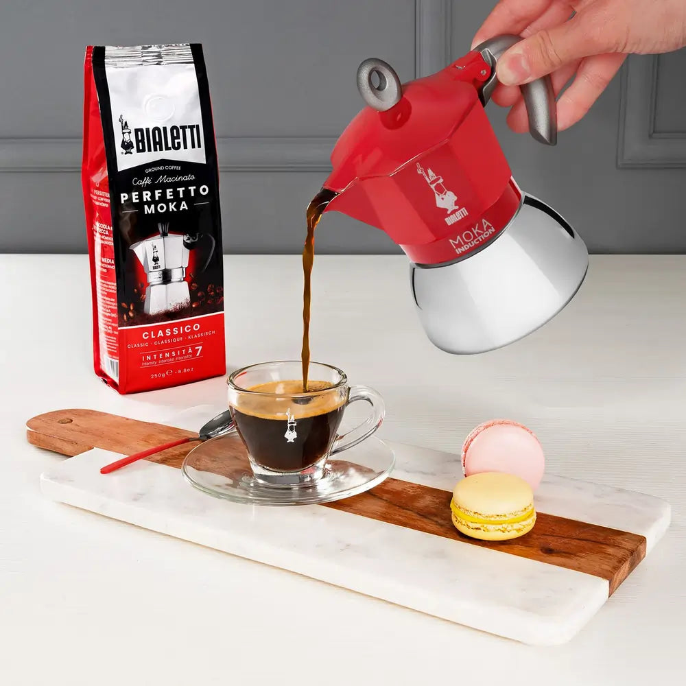Parzenie kawy w czerwonej kawiarce Bialetti Moka Induction, nalewanie espresso do filiżanki