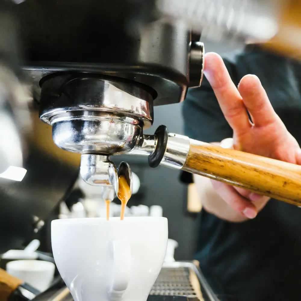 Zbliżenie na ekstrakcję espresso z kolby do filiżanki w kawiarni speciality