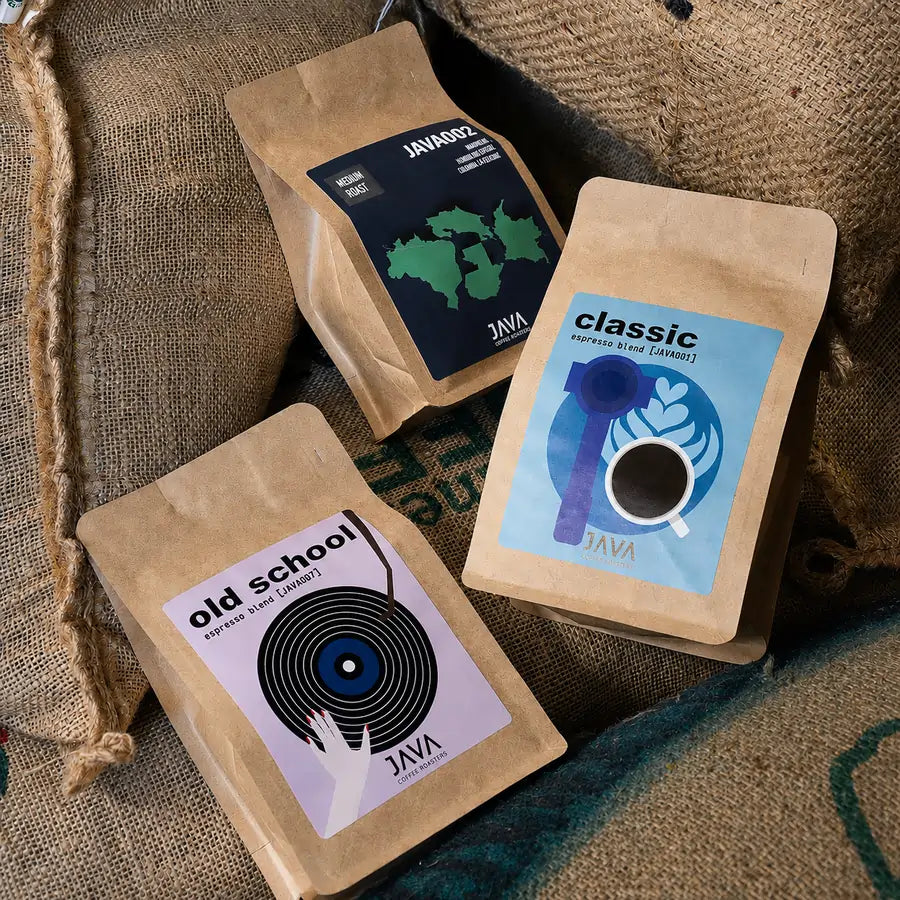 Kawy espresso JAVA Coffee Roasters – Classic, Old School i JAVA002 na workach jutowych z zieloną kawą w palarni kawy specialty.