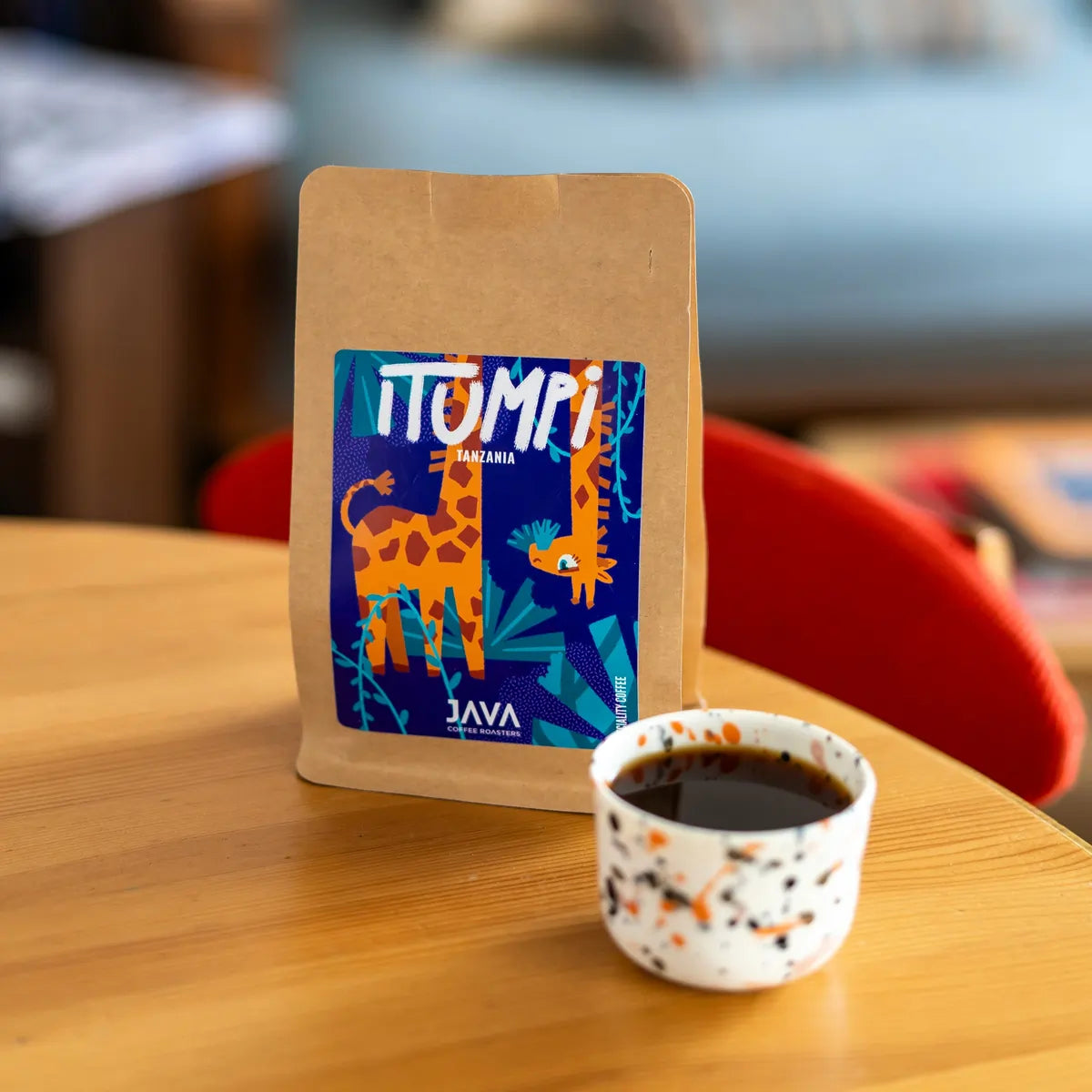 Kawa specialty Tanzania Itumpi 250 g od JAVA Coffee Roasters z filiżanką czarnej kawy na drewnianym stole w kawiarni