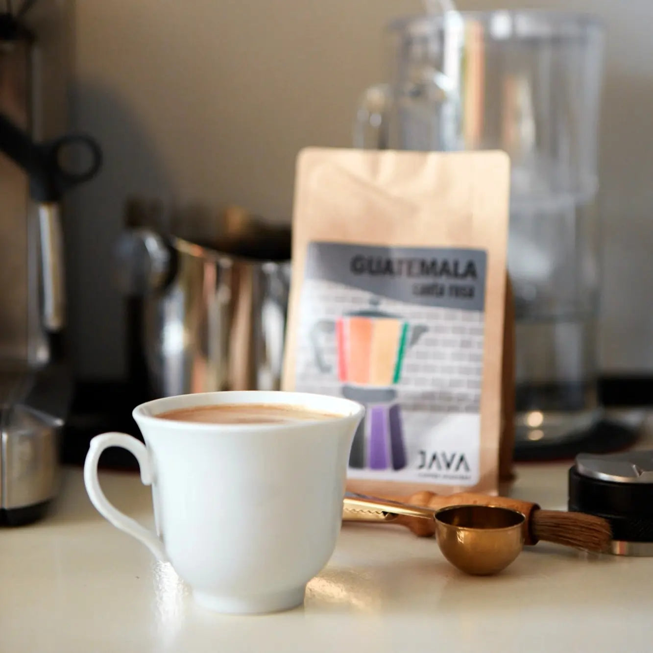  Filiżanka kawy przygotowanej z ziaren Guatemala Santa Rosa od JAVA Coffee – scena domowego parzenia z akcesoriami baristy w tle.