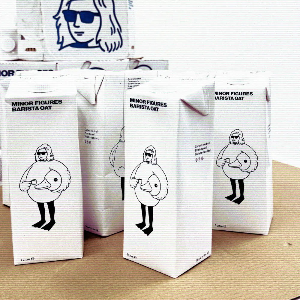 Litrowe kartony napoju owsianego Minor Figures Barista Oat ustawione na kartonie – minimalistyczne opakowania z ilustracją postaci w przebraniu ptaka, trzymającej filiżankę kawy.