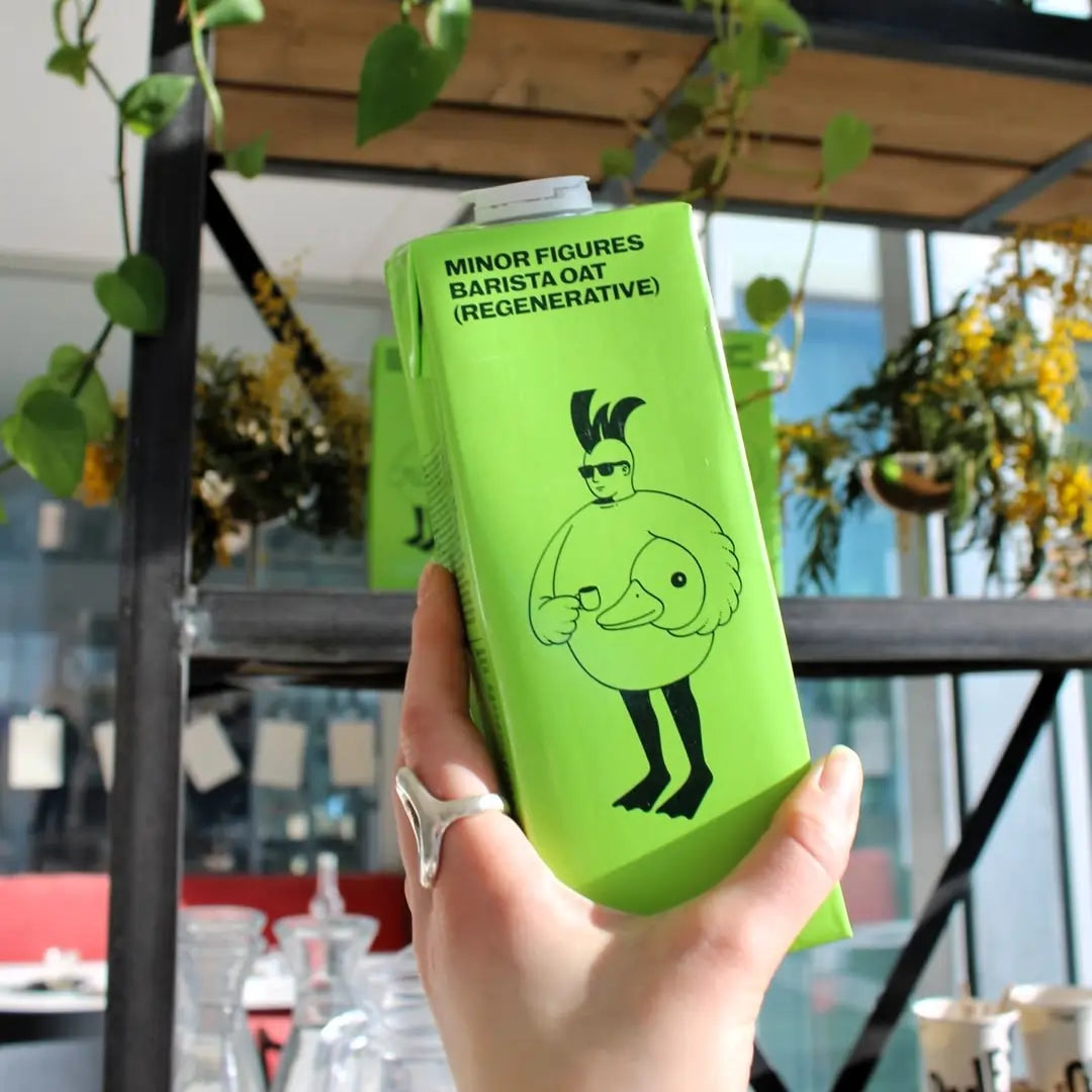 Minor Figures Barista Oat Regenerative napój owsiany – karton trzymany w ręce w kawiarni, mleko roślinne do kawy