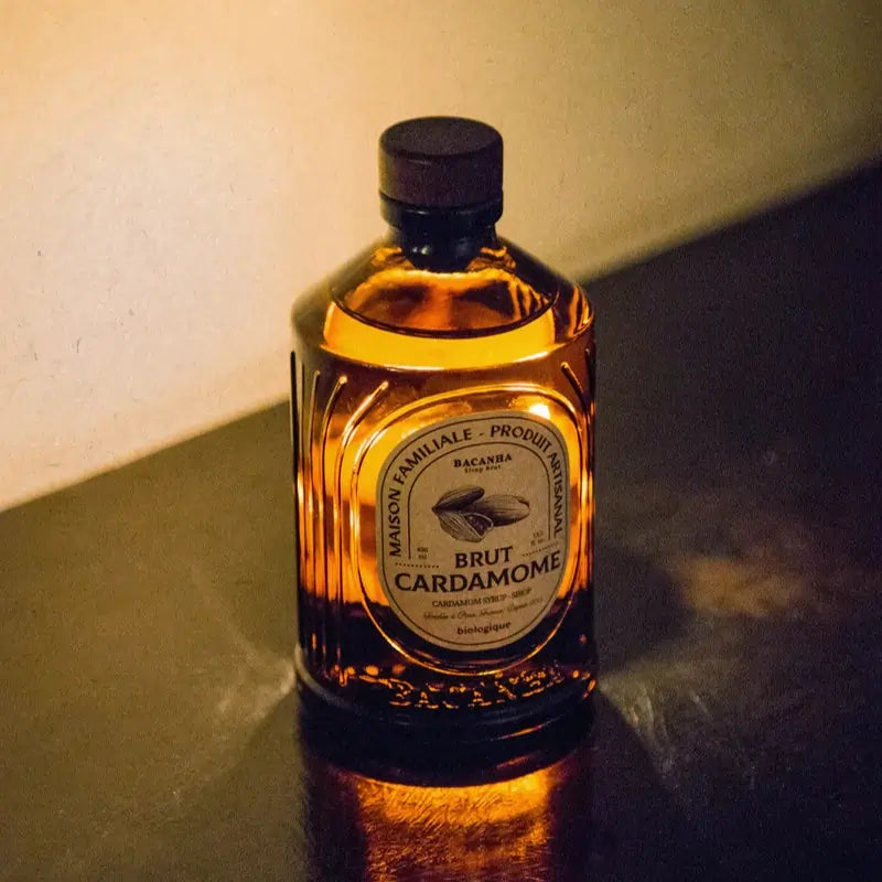Syrop Bacanha o smaku kardamonu 400 ml – organiczny syrop w bursztynowej butelce, oświetlony ciepłym światłem