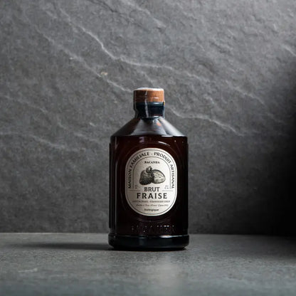 Syrop Bacanha o smaku truskawkowym – organiczny syrop w bursztynowej butelce na kamiennym tle