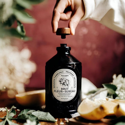 Organiczny francyzski syrop Bacanha o smaku kwiatu czarnego bzu na stole w otoczeniu