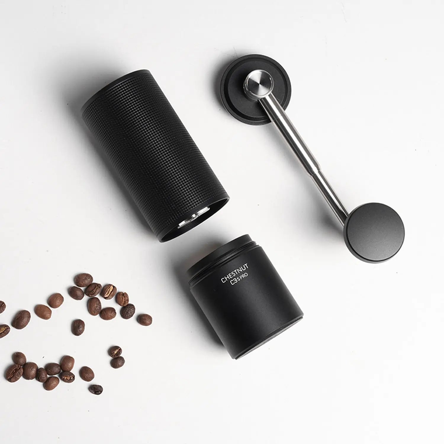  Rozłożony młynek ręczny Timemore Chestnut C3s Pro Black z ziarnami kawy na białym tle – widoczne elementy: korpus, pojemnik i rączka.